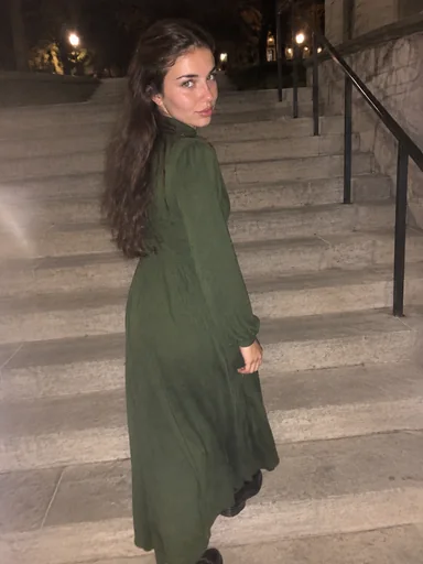 The character on outdoor stairs at night in a green dress